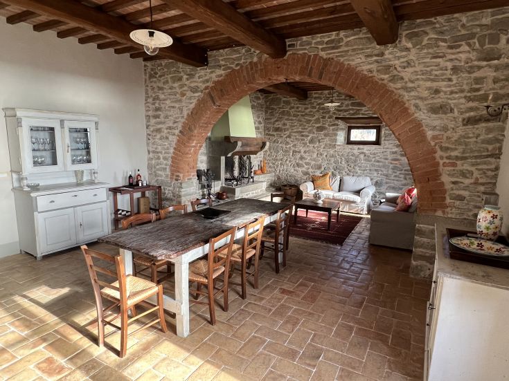 A bright and spacious kitchen in a traditional Umbrian farmhouse, with natural wood furniture and stone details.