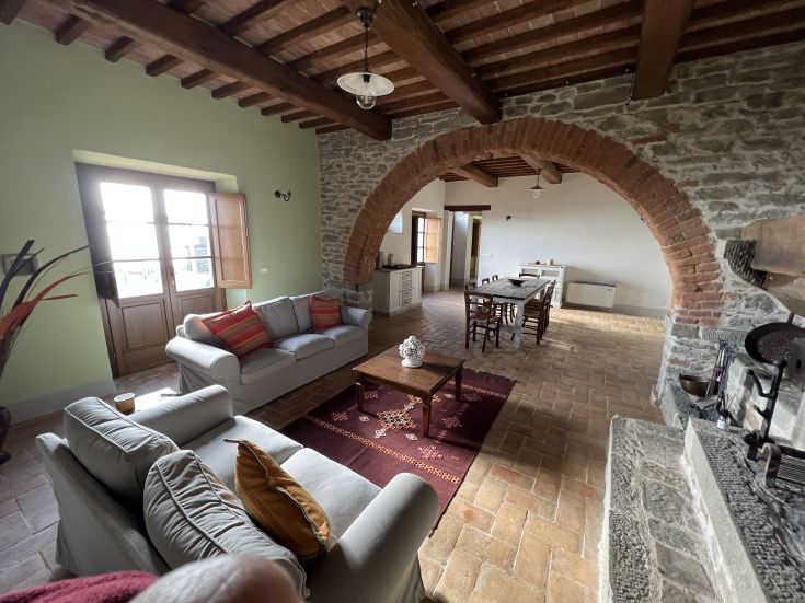 Simple interior of a farmhouse in Umbria with exposed beams and wooden furniture.