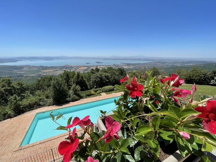 A tranquil lake scene surrounded by greenery, featuring a pool and colorful flowers in the foreground.