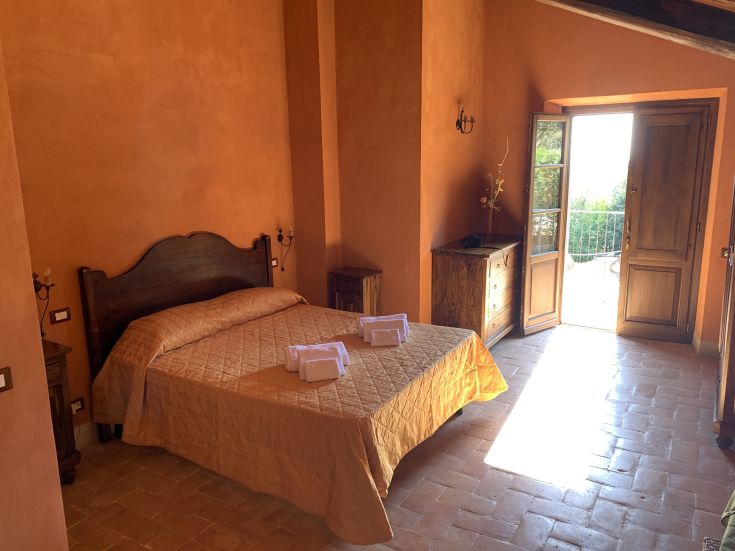Spacious room in a rustic villa with a view of the garden and direct access to the balcony.