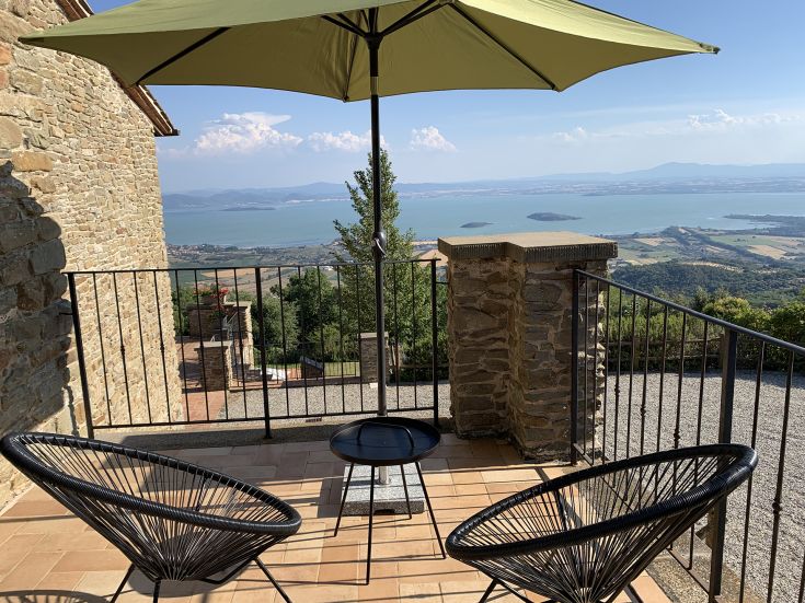 A panoramic view of Lake Trasimeno from a villa in Umbria, surrounded by the greenery and tranquility of nature.