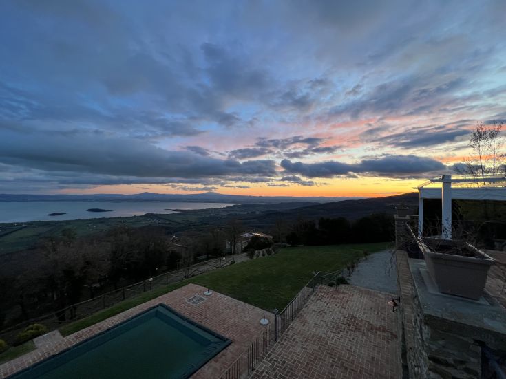 Breathtaking sunset over Lake Trasimeno, surrounded by lush green hills.
