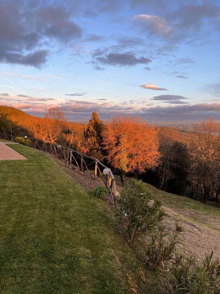 A sunset scene showcasing an Umbrian landscape, highlighting green hills and colorful sky gradients.