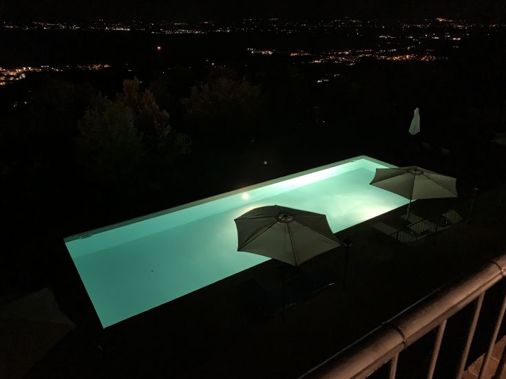 A beautifully lit swimming pool at night, surrounded by umbrellas and relaxation areas for a calm retreat.