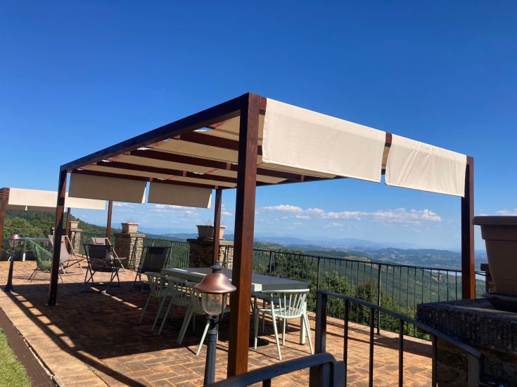 A simple pergola on a terrace, surrounded by green plants. A space perfect for relaxation and gatherings.