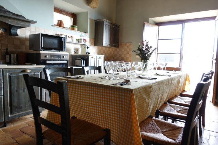 Simple interior of a villa in Umbria, with decorated table and light coming from the windows.