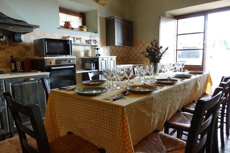 An inviting kitchen with a long dinner table set and a view of the surrounding countryside.