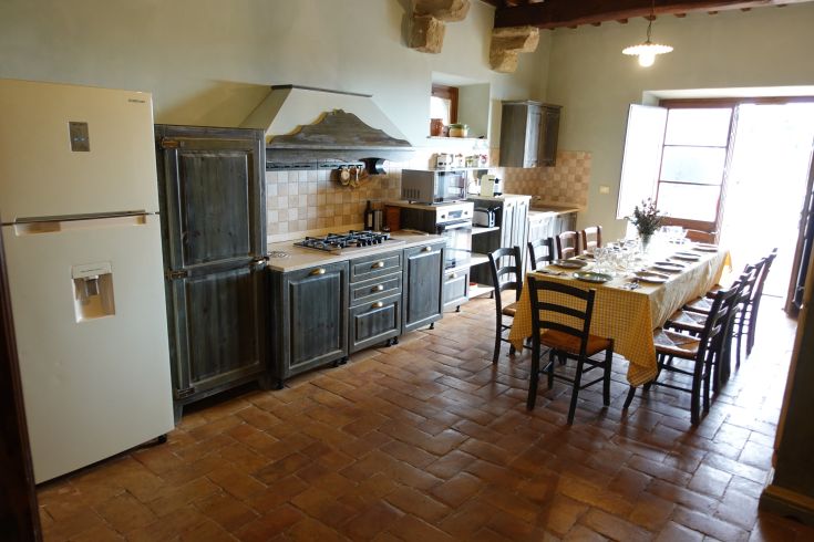 A spacious kitchen with rustic elements and a large table for shared meals.