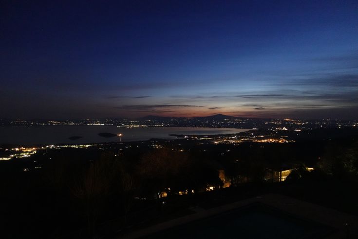 Serene scene of Lake Trasimeno at sunset, with golden reflections on the water and surrounding landscape.