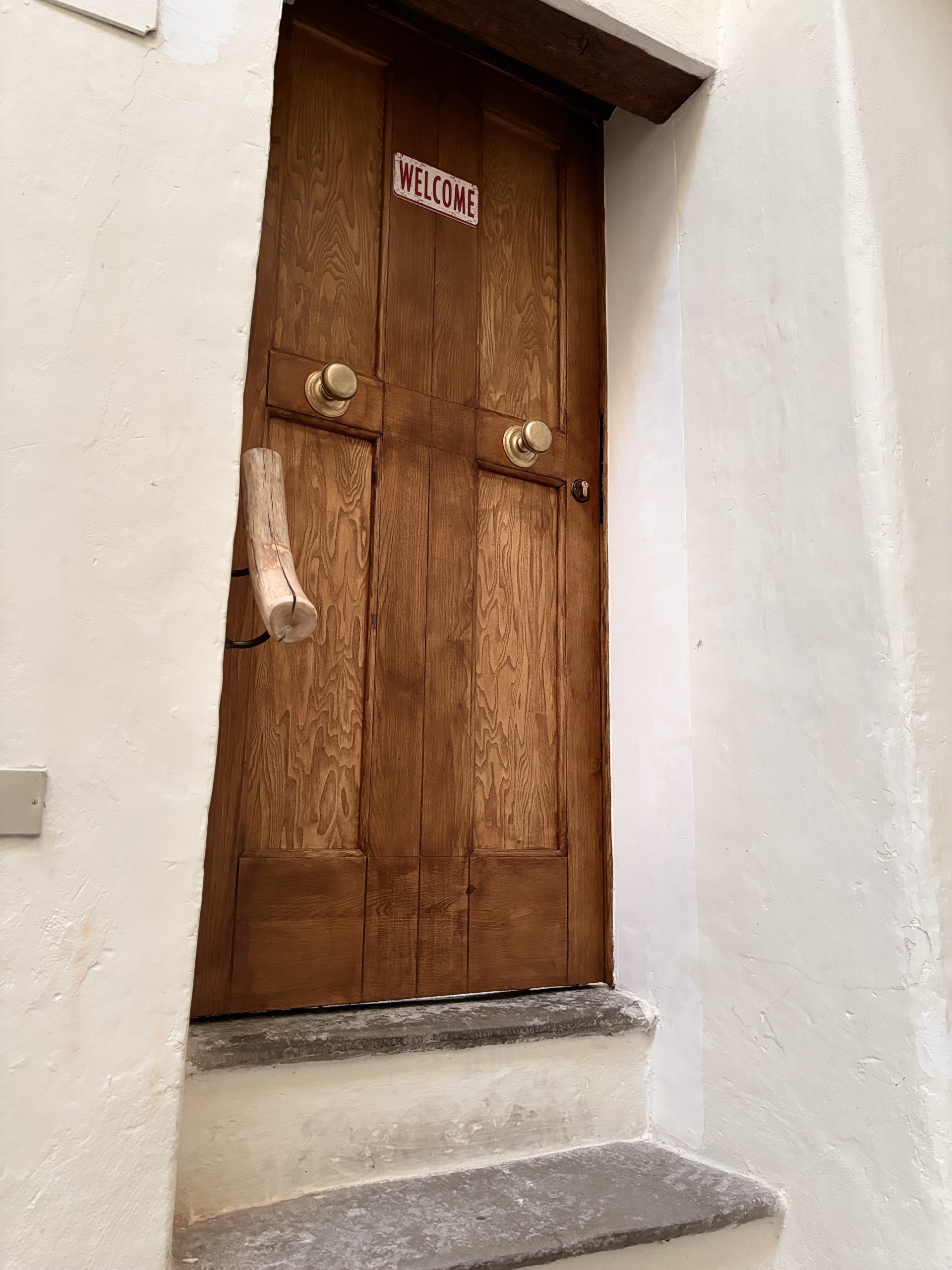 Porta in legno con una scritta accogliente, che invita a entrare in un ambiente sereno e ospitale.