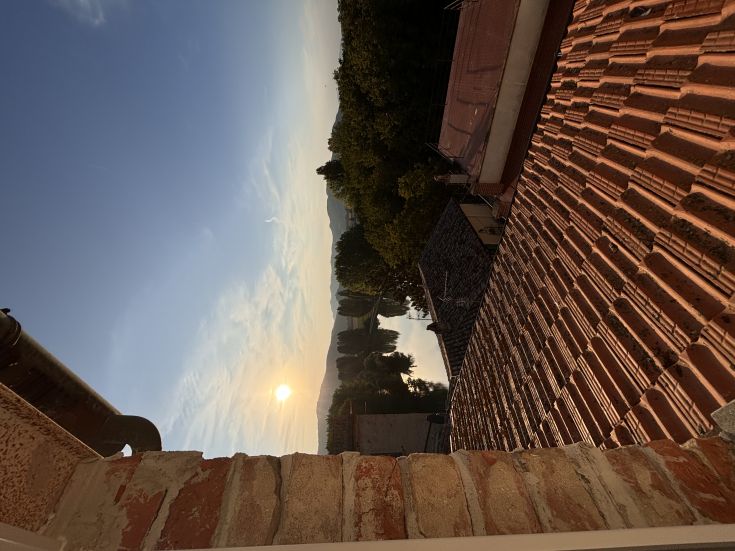 Scena dell'alba con il sole che sorge sopra i tetti di un casolare.