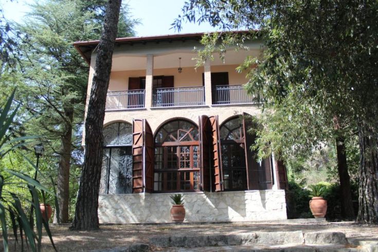 Grande villa avec terrasse située dans la verdure, idéale pour des moments de détente dans un environnement paisible.