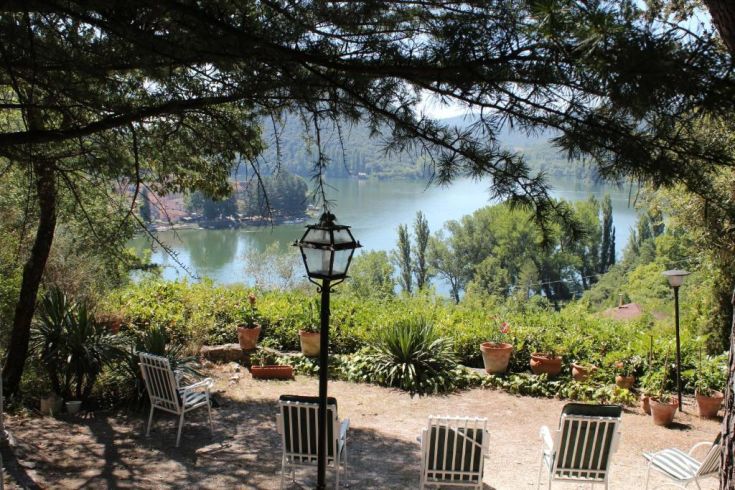 Une villa donnant sur le lac, avec des places assises en extérieur et entourée de verdure.