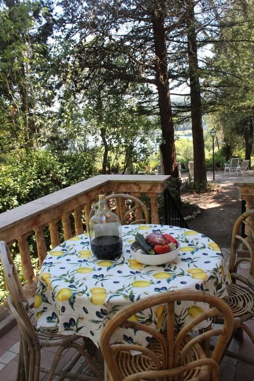 Une table joliment dressée avec une nappe à motif de citrons, entourée d'arbres et donnant sur le lac.