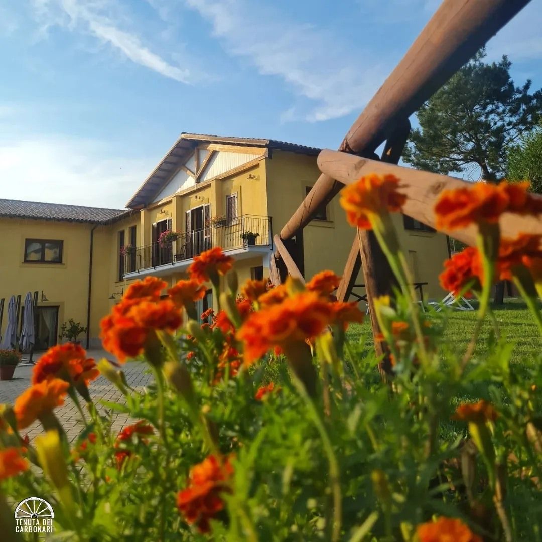 Un edificio circondato da vegetazione, con fiori e un cielo sereno.