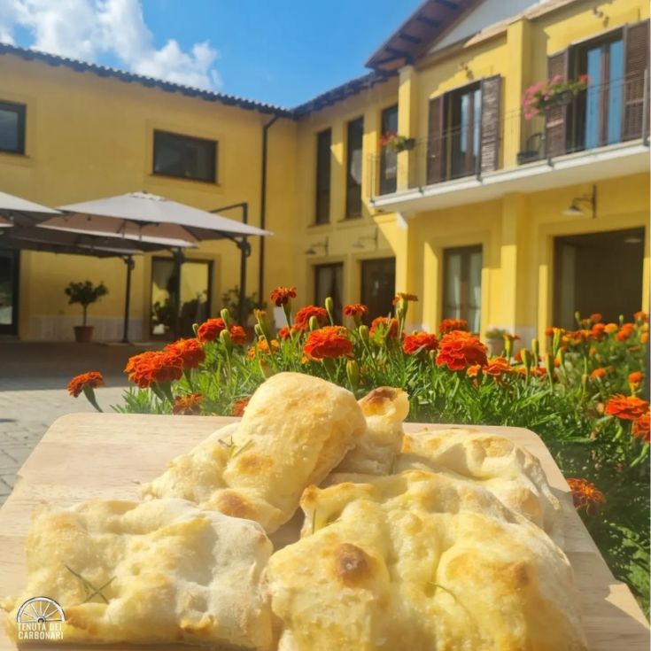 Focacce fresche servite in un'accogliente tenuta, circondata da un giardino con fiori variopinti.