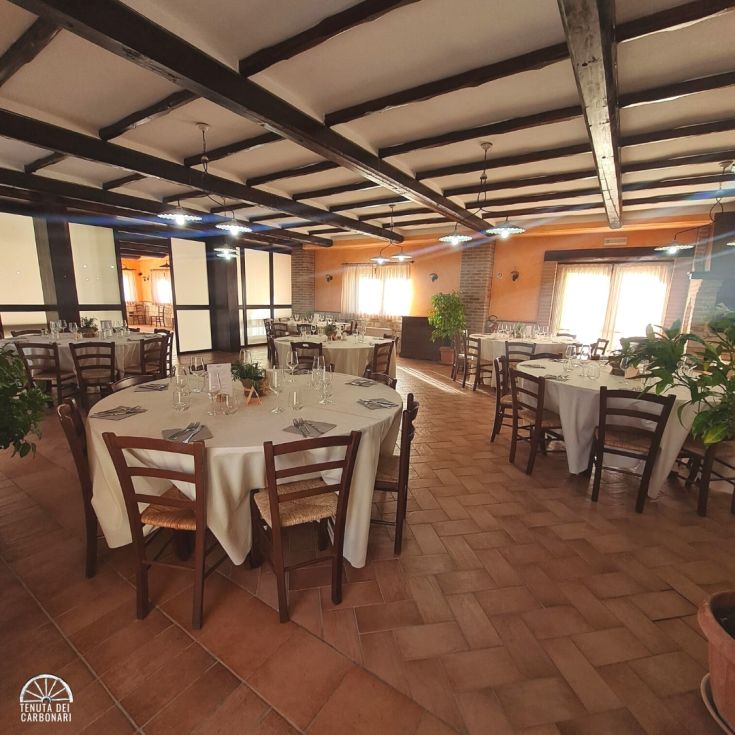 Interno di un ristorante con tavoli allestiti per un evento, in un ambiente curato e accogliente.