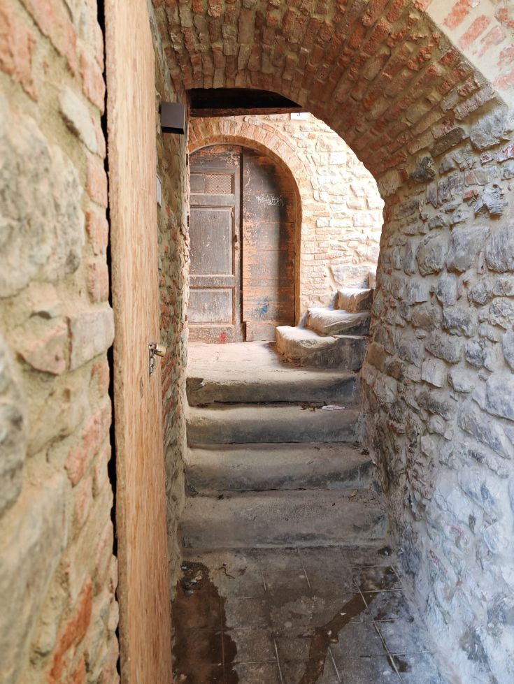 A passage in a medieval village, featuring stone steps and wooden doors.