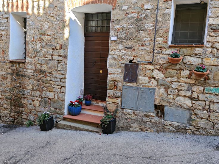 Entrance of the palace featuring exposed stones and blooming plants, typical of a medieval village.