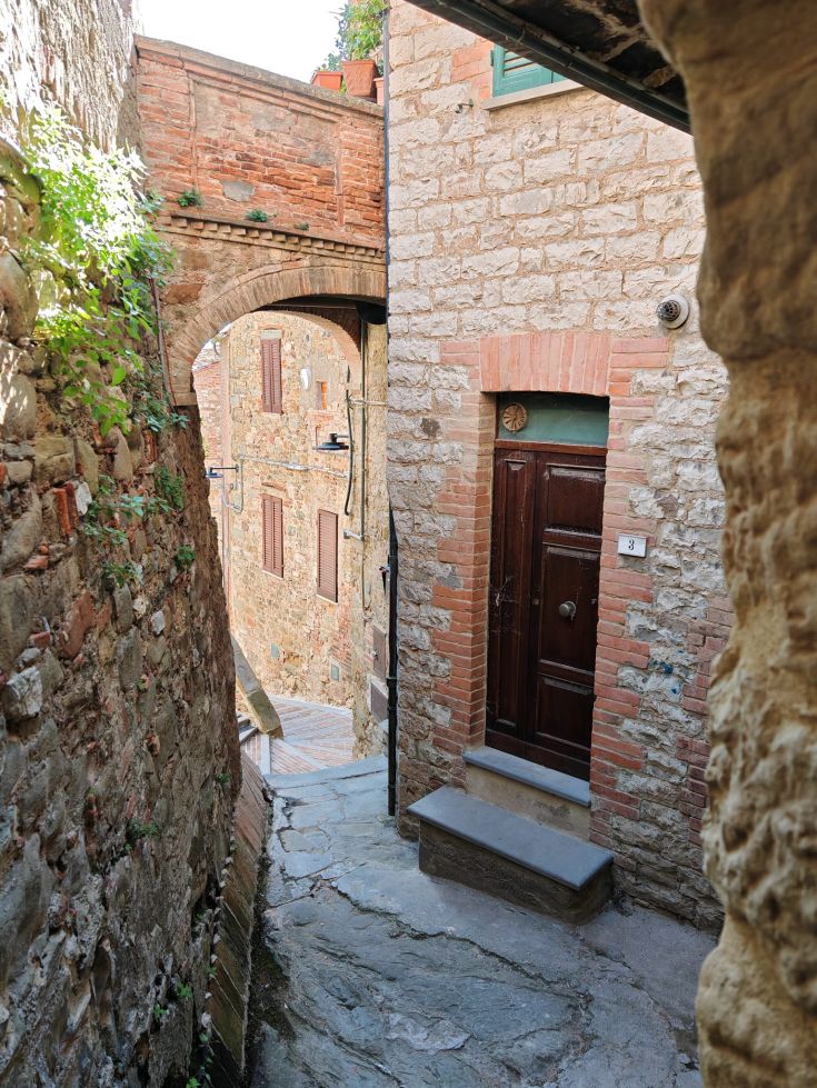 A medieval alley featuring arches and stone buildings.
