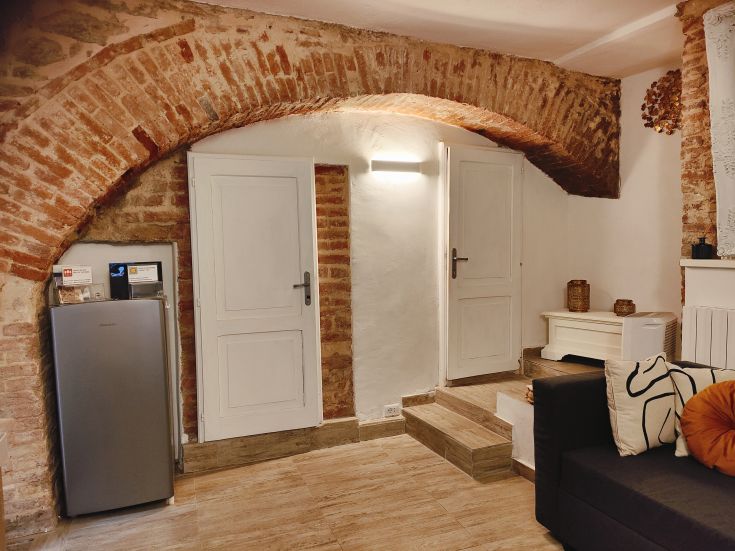 Indoor space with brick arches, featuring a fully equipped kitchen and a refrigerator.