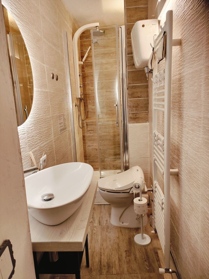 A simple bathroom featuring a shower, sink, and understated finishes.