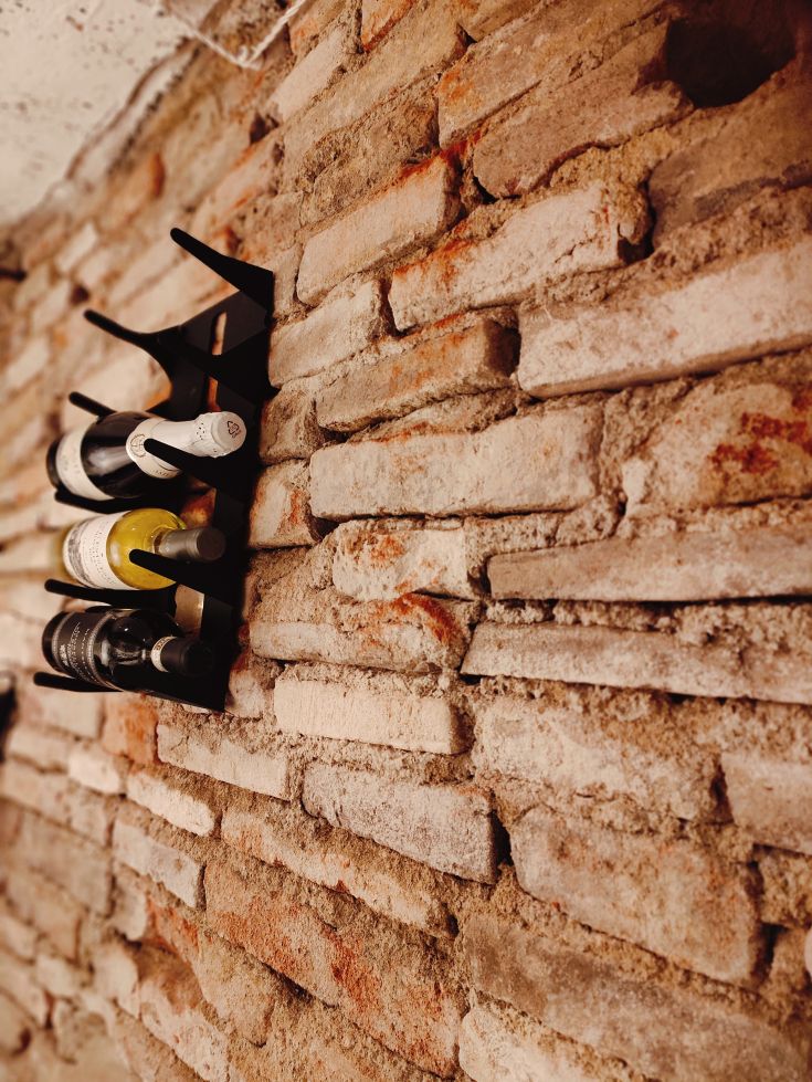 A metal bottle holder mounted on a brick wall. Simple and functional.