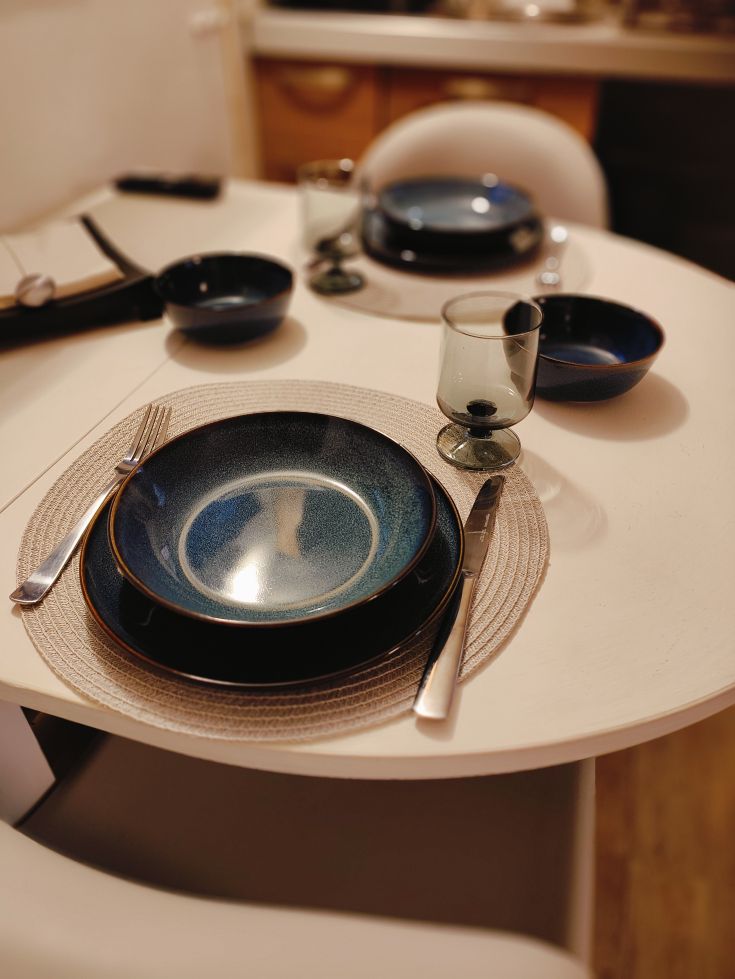 The table is elegantly set with fine plates and glasses. The ambiance is warm and welcoming, perfect for a dinner among friends.