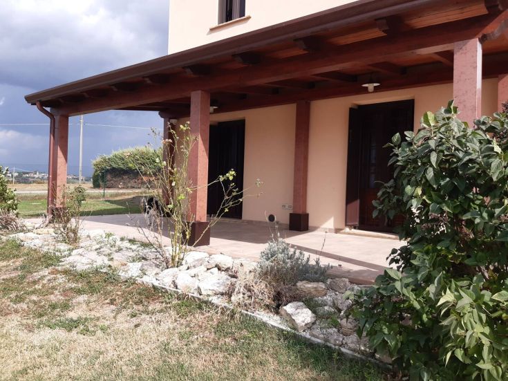 Gebäude umgeben von Grün, mit einer großen Veranda und einem gepflegten Garten, ideal für ruhige Momente.