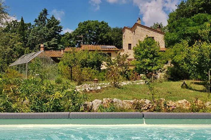 Ein historisches Gebäude in Umbrien, umgeben von einem Garten, mit einem Pool und einem Wellnessbereich, perfekt für einen entspannenden Urlaub.