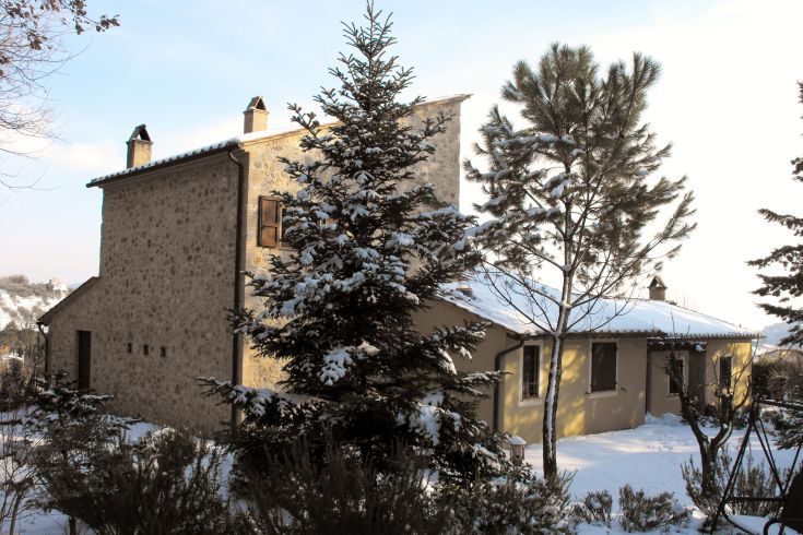 Un grand palais recouvert de neige, situé dans un jardin paisible en Ombrie.