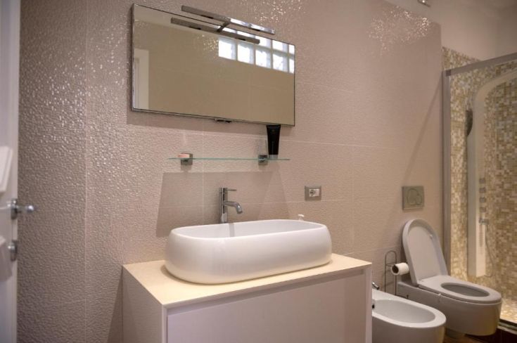 Bagno con design semplice, dotato di lavabo e accessori dai toni neutri.