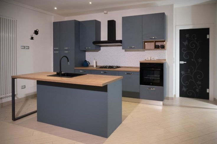 Cucina contemporanea con isola al centro, mobili grigi e particolari in legno chiaro.