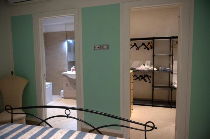 Camera con accesso a un bagno e un armadio ben sistemato.