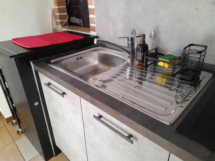 Cuisine contemporaine avec évier et ustensiles, dans un espace au design épuré.