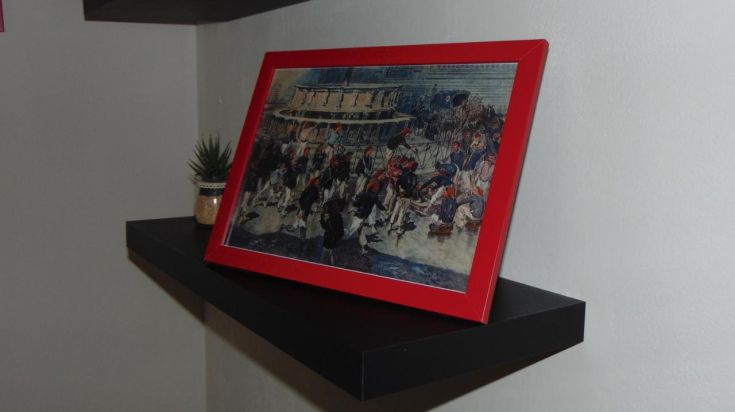 Une peinture encadrée reposant sur une étagère dans un environnement simple et bien éclairé.