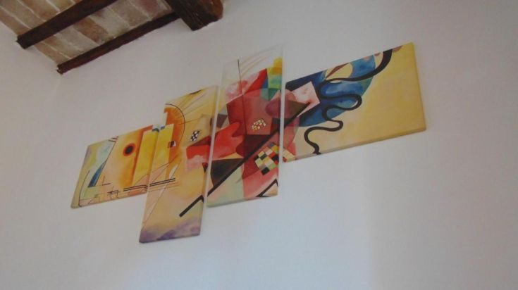Une peinture moderne aux couleurs vives et formes abstraites sur un mur neutre.