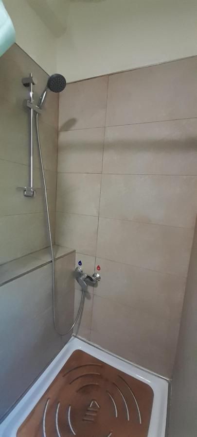 Douche simple dans une salle de bain rénovée avec des carreaux clairs et des accessoires pratiques.
