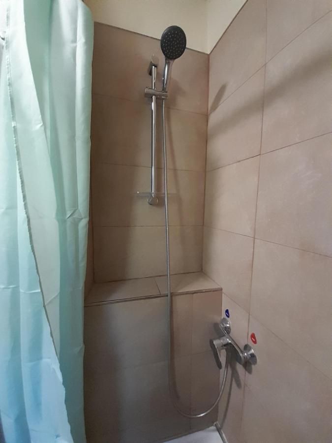Douche dans une salle de bain privée, avec des murs carrelés et un rideau bleu pour la vie privée.