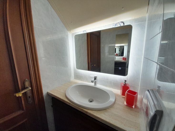 Une salle de bain moderne avec un miroir lumineux, un évier fonctionnel et des accessoires colorés. Ambiance relaxante.