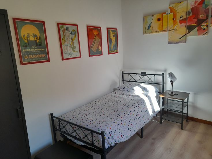 Chambre spacieuse avec un lit simple, un ameublement simple et une lumière naturelle créant une ambiance accueillante.