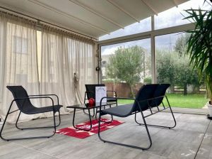 Ambientazione confortevole con poltrone e un tavolo, affacciata su un giardino verde.