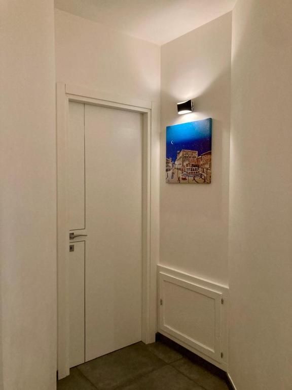 Un corridoio semplice con una porta di colore bianco e un quadro dai colori vivaci che arricchisce l'ambiente.
