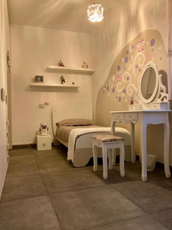 Cameretta semplice e luminosa con letto singolo, un ampio specchio e alcune decorazioni colorate sulle pareti.