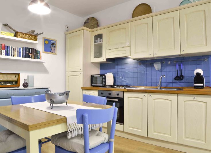 Cuisine fonctionnelle avec des meubles clairs, une table en bois et des décorations simples.