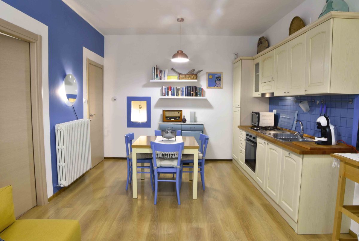 A modern kitchen featuring blue tones and minimalist furniture, perfect for social gatherings.