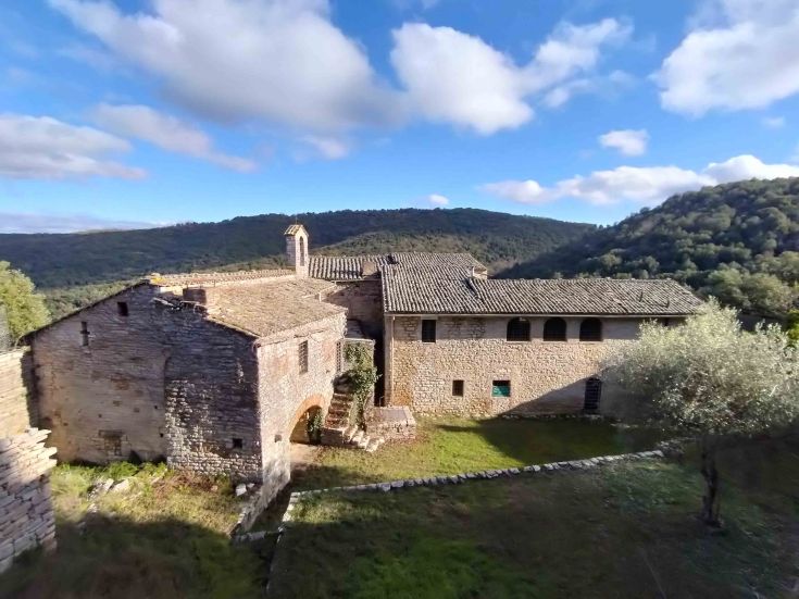 Un complexe ancien entouré par la nature, avec des collines verdoyantes en arrière-plan.