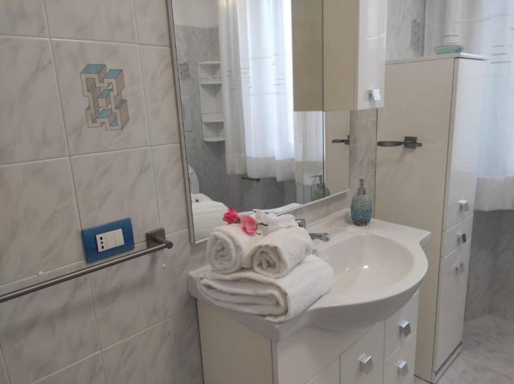 Un bagno con design moderno, dotato di finiture chiare, asciugamani bianchi e decorazioni semplici.