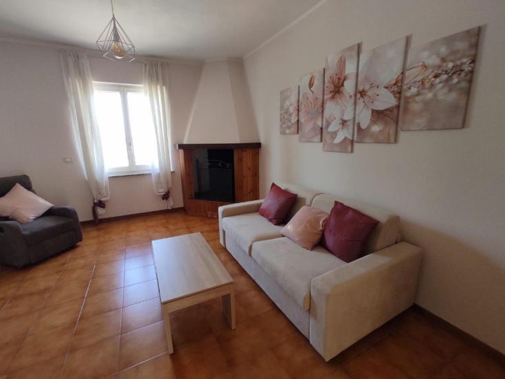 Soggiorno semplice con divano e alcune decorazioni floreali, adatto per momenti di relax e incontro.