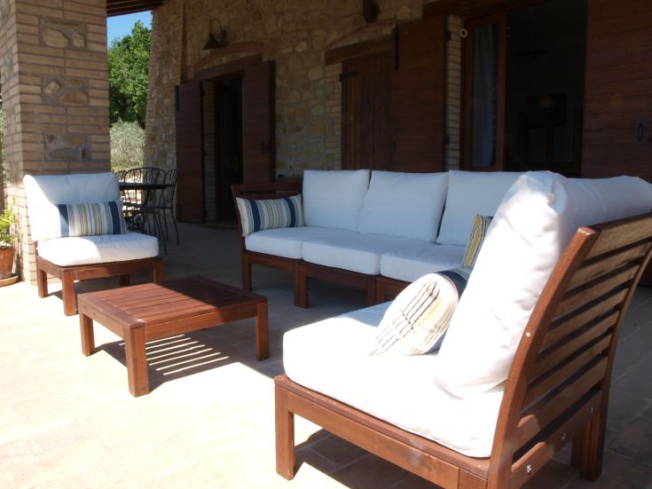 Außenbereich mit hellen Sofas und einem Holztisch, ideal für entspannte Momente.